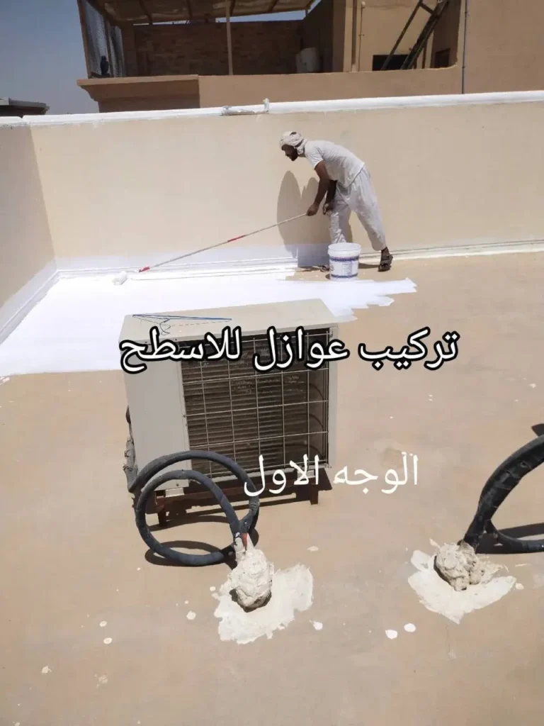 فني يطبق طبقة العزل الأبيض بالقرب من مكيف هواء قديم على سطح مبنى بالدمام