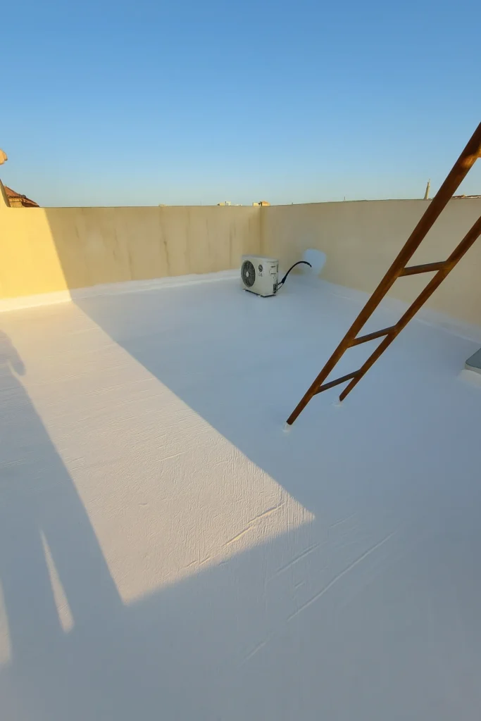 سطح منزل معزول بطبقة عزل مائي بيضاء، يظهر مكيف خارجي مثبت على السطح وسلّم حديدي